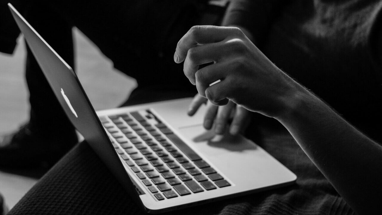 grayscale photo of person using MacBook